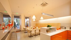 A modern kitchen with orange cabinets, a white countertop, and pendant lighting. - Porto Lounge Hostel & Guesthouse (Porto)