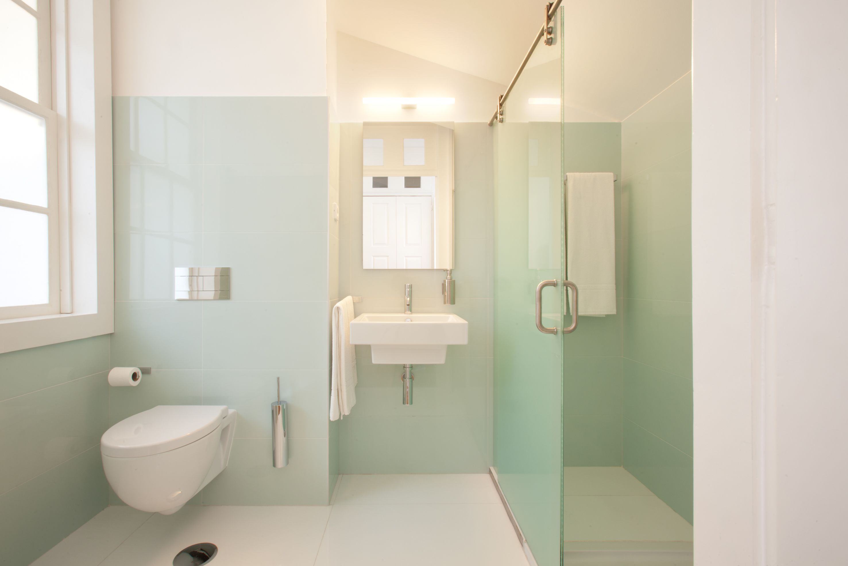 Une salle de bain moderne équipée de toilettes, d’un lavabo et d’une douche à parois de verre.