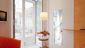 A modern living room with a sofa, a floor lamp, and a view through a glass door. - Porto Lounge Hostel & Guesthouse (Porto)