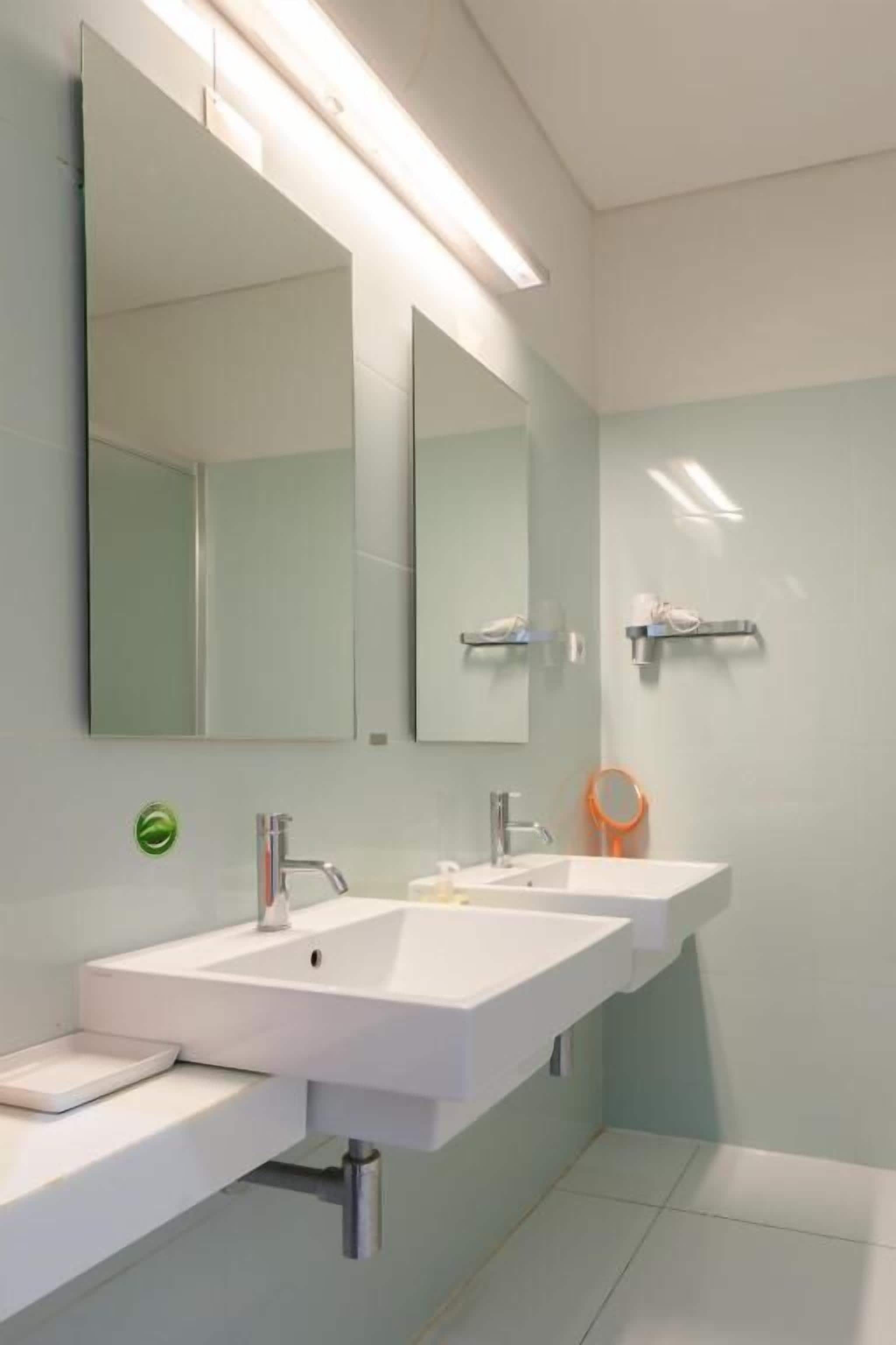 A modern bathroom with two sinks, a large mirror, and a towel rack.