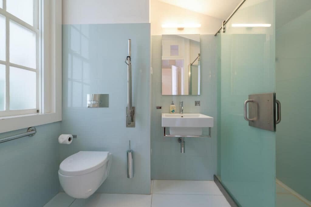 A modern bathroom with a toilet, a shower, a sink, and a mirror.