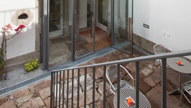 A multi-level outdoor terrace with a glass door entrance, stone flooring, and metal railings. - Porto Lounge Hostel & Guesthouse (Porto)