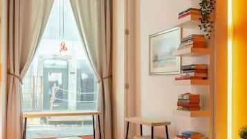 A modern room with a large window, a bookshelf, and a seating area.