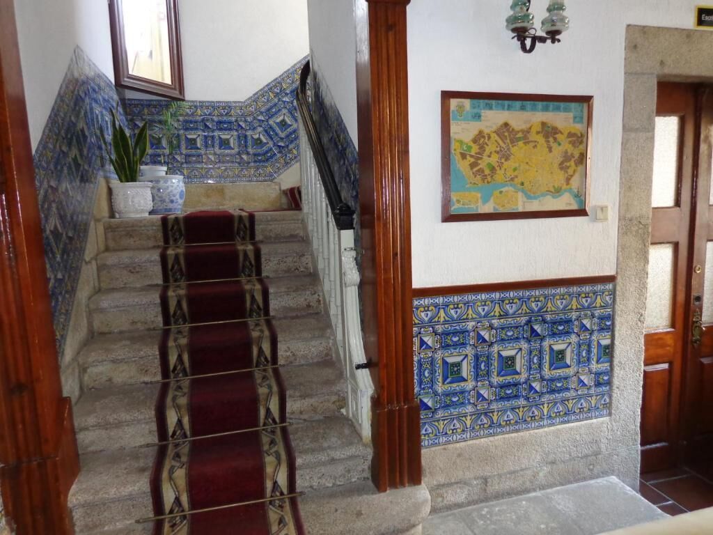 A staircase with blue and white patterned tiles, a wooden handrail, and a red carpet.