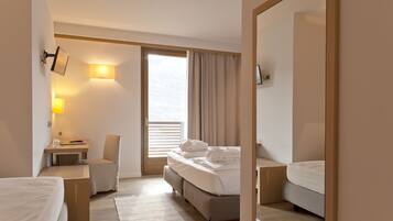 Een hotelkamer met een bed, een bureau, een stoel en een groot raam met gordijnen.