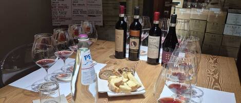 Una mesa de madera con copas de vino, botellas y un cartel de menú al fondo.