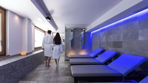 A spa area with massage tables and a stone wall with a water feature.