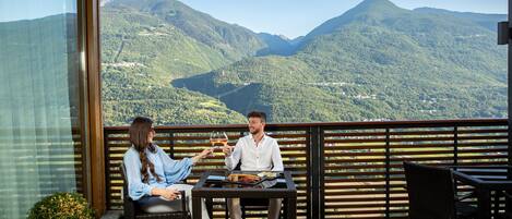 Un balcon avec une table et des chaises, donnant sur un paysage montagneux.