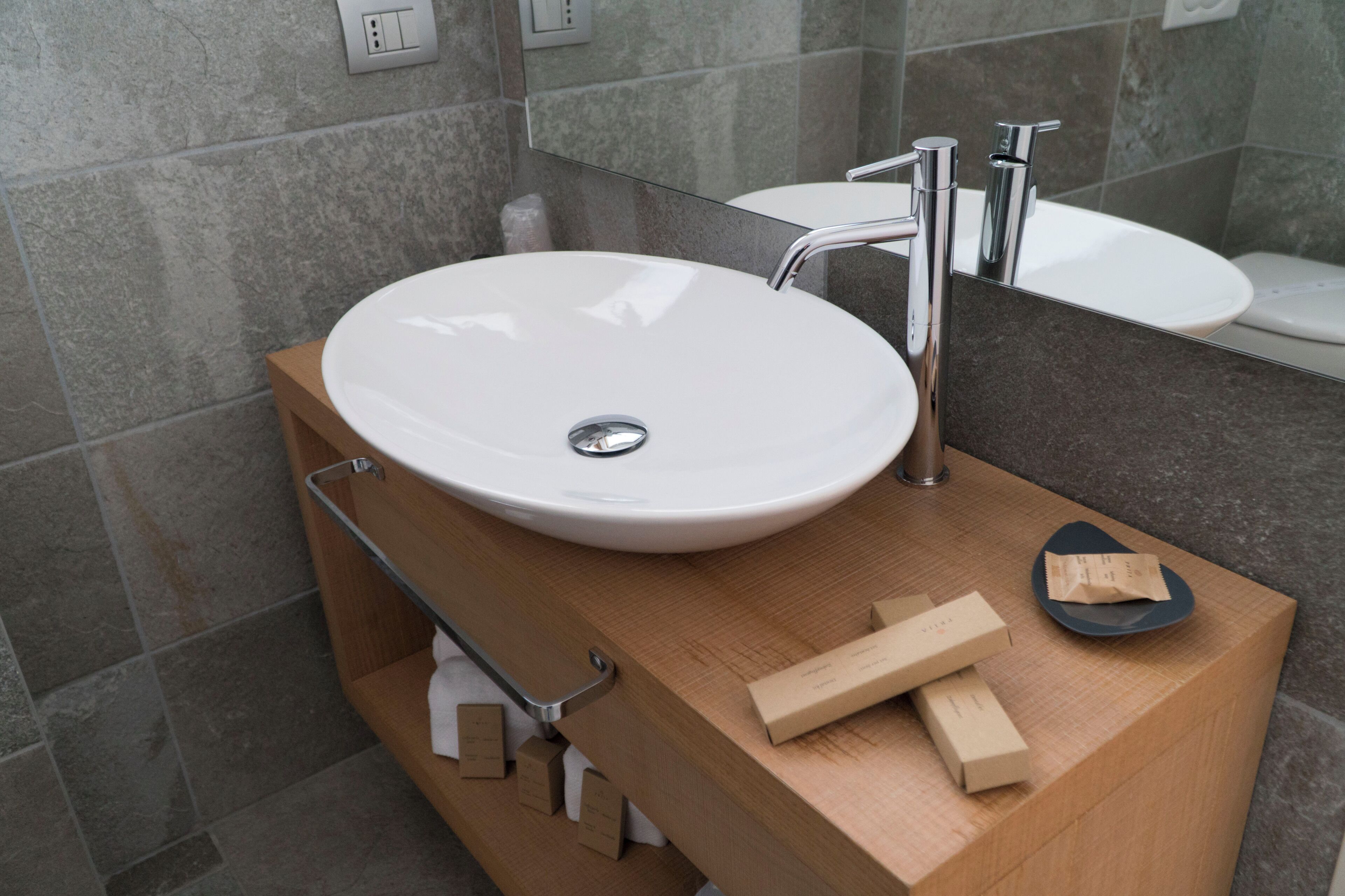 Ein modernes Badezimmer mit einem weißen Waschbecken, einem Spiegel und einer Holzausstattung.
