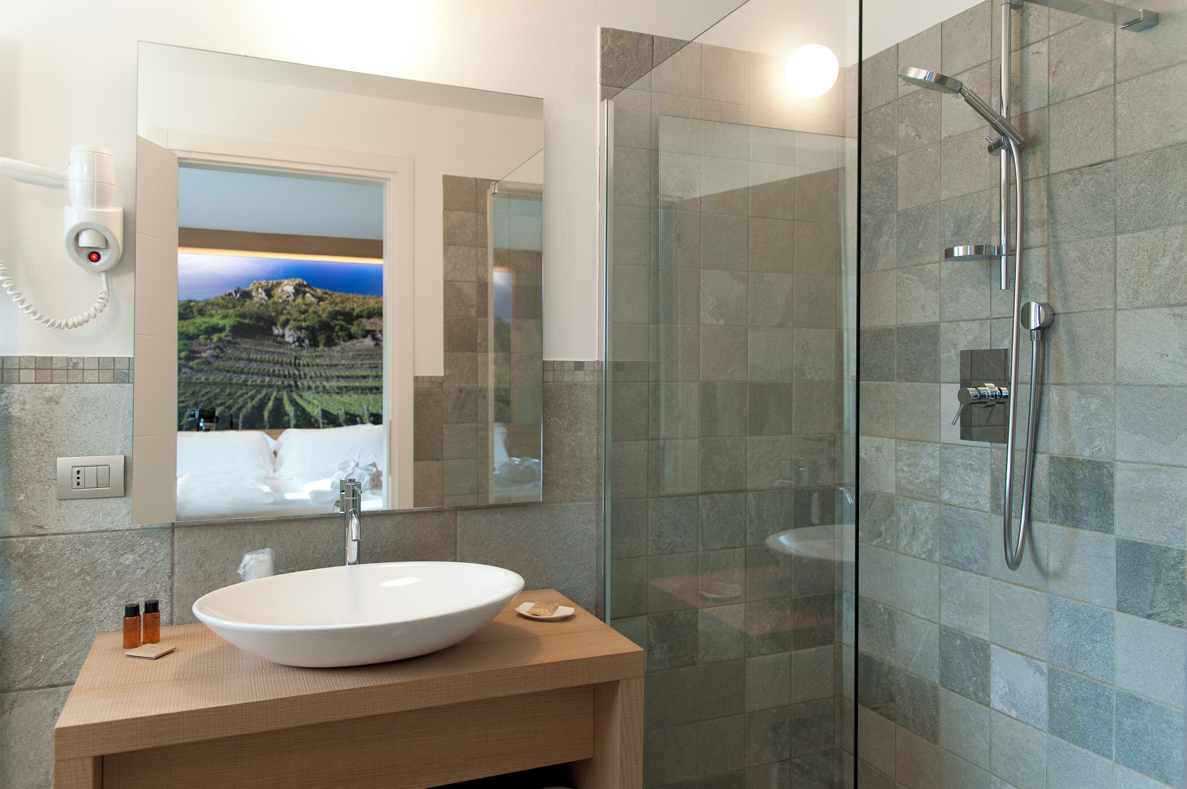 A modern bathroom with a large mirror, a sink, and a glass-enclosed shower.