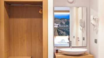 A bathroom with a wooden vanity, a large mirror, and a view of a vineyard through the window.