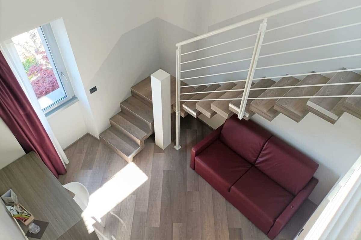 A modern interior with a staircase, a red sofa, and a dining area.
