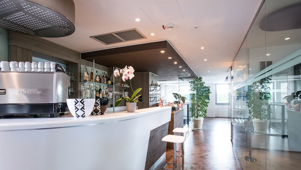 A modern bar area with a stainless steel refrigerator, bar stools, and a variety of bottles on shelves. - Hotel Corte del Paggio (Valeggio sul Mincio)