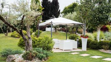 Un jardin agrémenté d’un kiosque blanc, d’un espace salon extérieur et de diverses plantes.