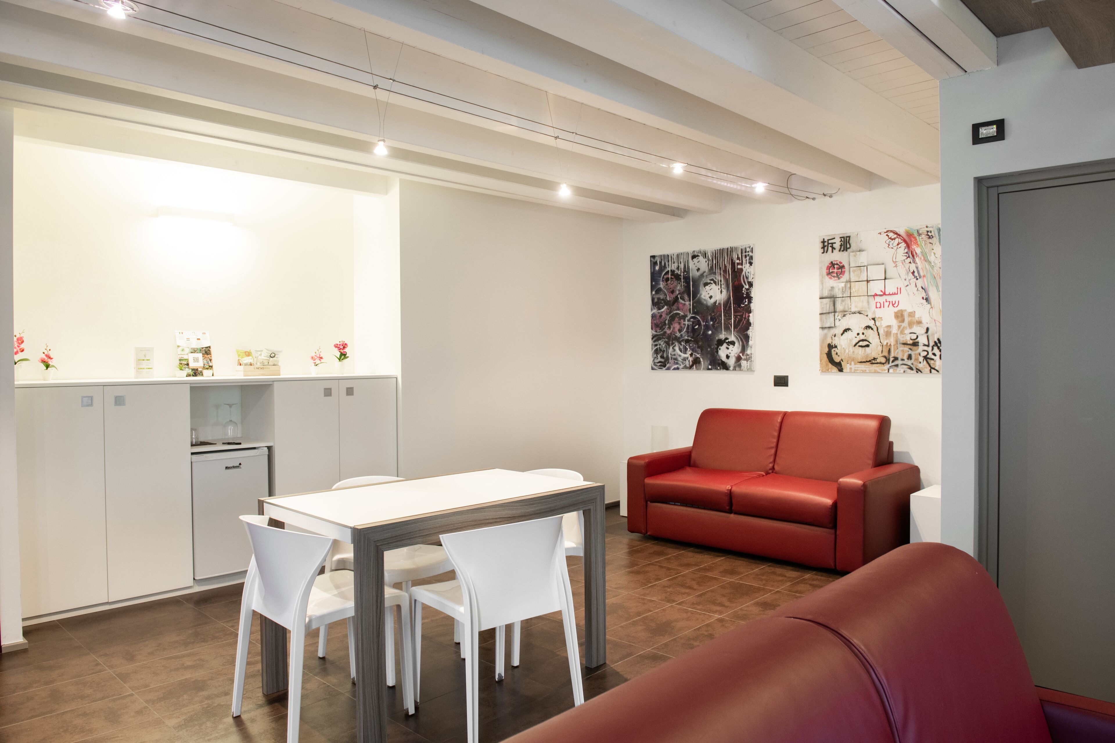 A modern interior with a dining area, a red sofa, and artwork on the walls.