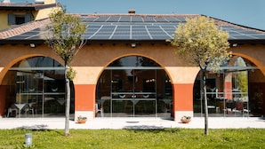 A building with a tiled roof, large glass windows, and a green lawn. - Hotel Corte del Paggio (Valeggio sul Mincio)