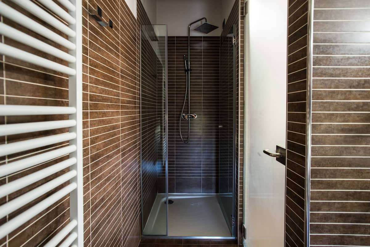 A modern shower area with a glass door, tiled walls, and a showerhead.