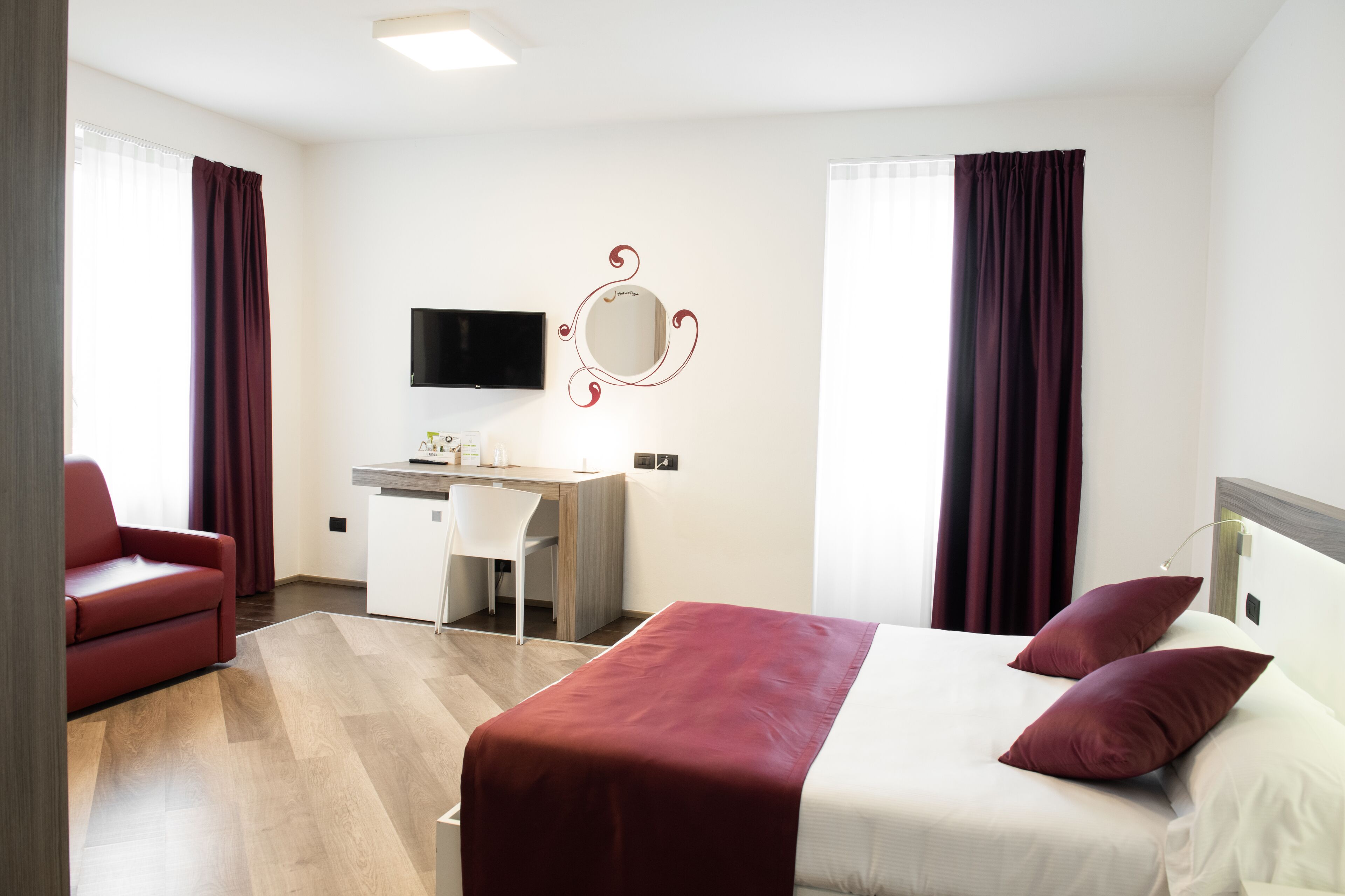 A hotel room with a bed, a desk, a chair, and a TV.