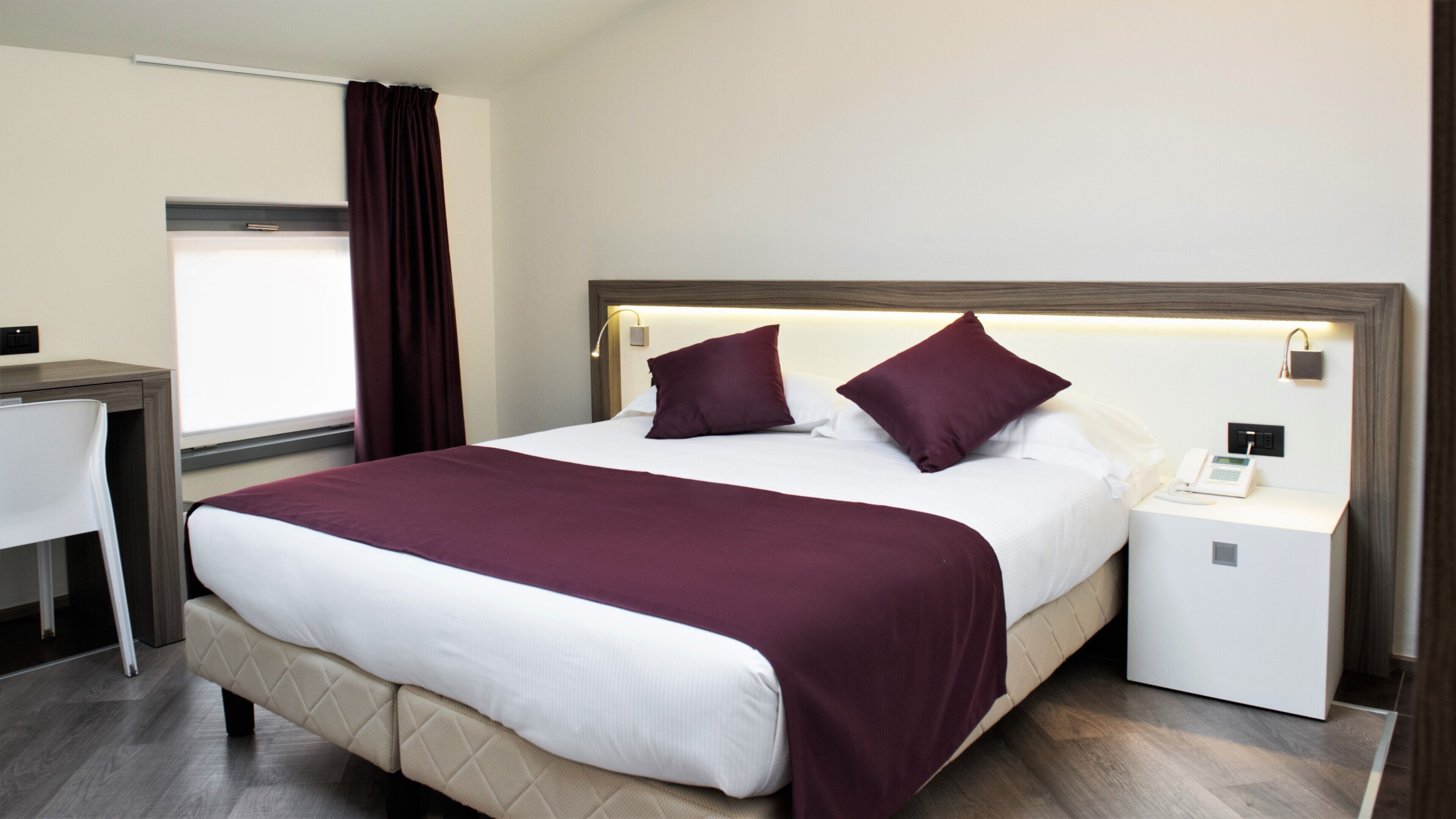 Ein Hotelzimmer mit Bett, Nachttisch und Schreibtisch.