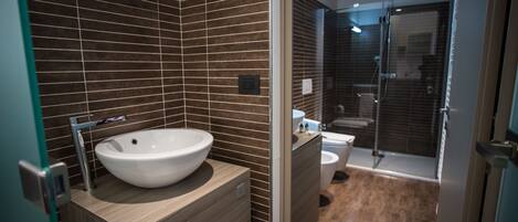 Un baño moderno con un lavamanos grande, inodoro y zona de ducha.