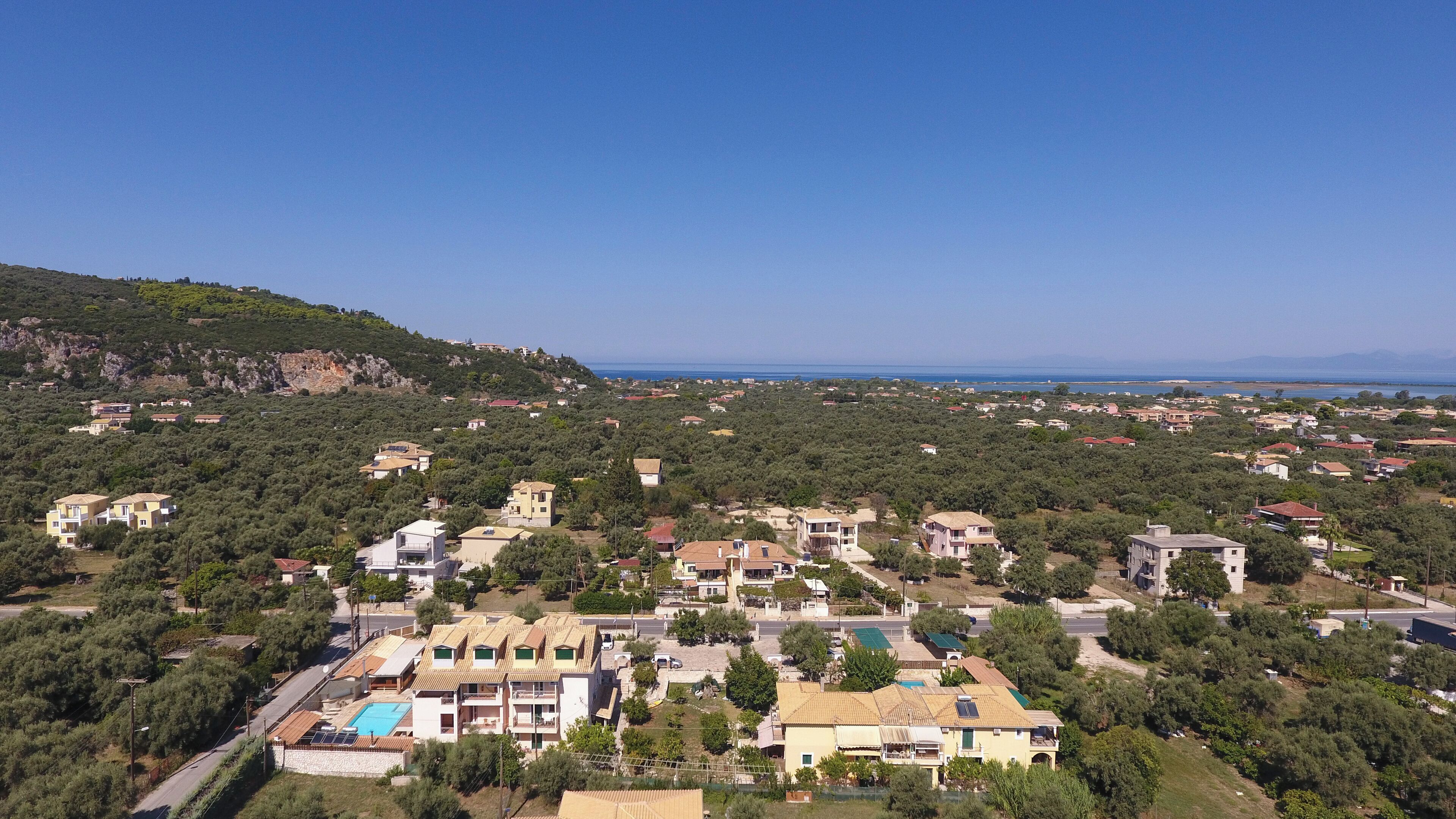 A residential area with houses, a swimming pool, and a hilly backdrop.