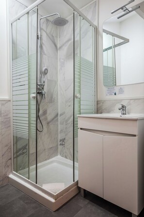 A modern bathroom with a glass-enclosed shower, a white vanity, and a mirror above the sink. - Oporto Maison Entreparedes (Porto)