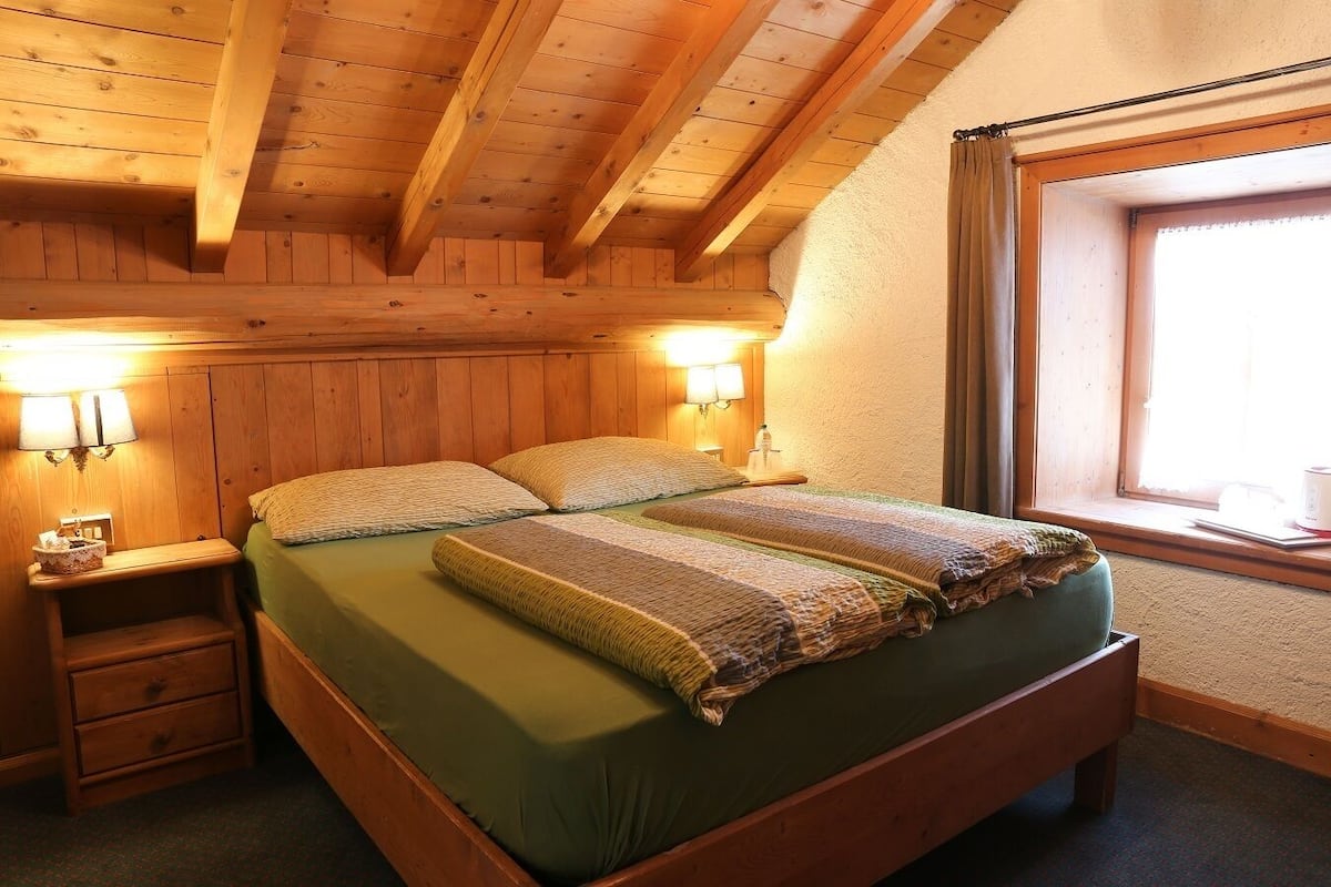 A wooden room with a bed, nightstands, and a window.
