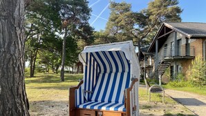 A beach chair with a striped cover, a wooden bench, and a metal chair nearby.