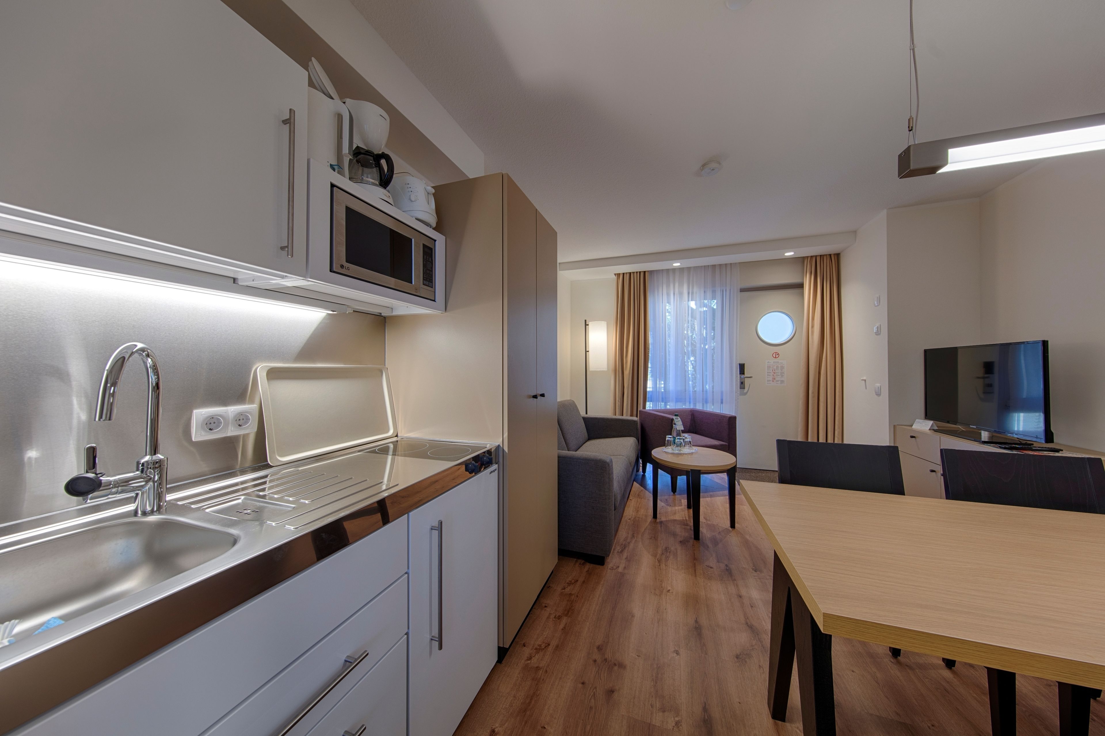 Une cuisine compacte équipée d’un évier, d’un four à micro-ondes et d’un coin repas avec une table et des chaises.