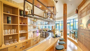 A bar area with wooden shelves, stools, and a mural.
