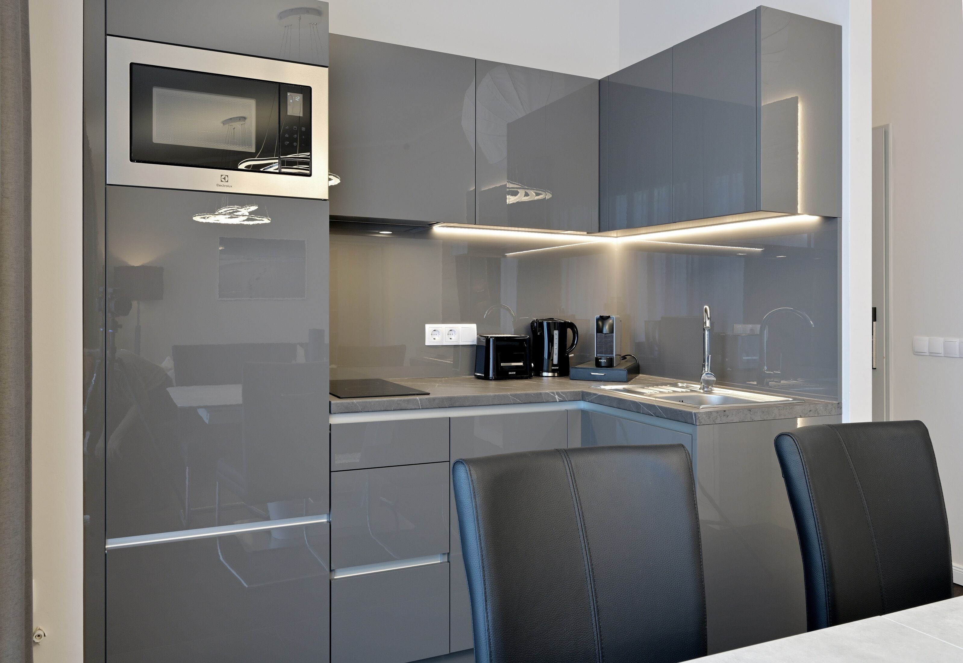 A modern kitchen with a built-in microwave, coffee maker, and sink.