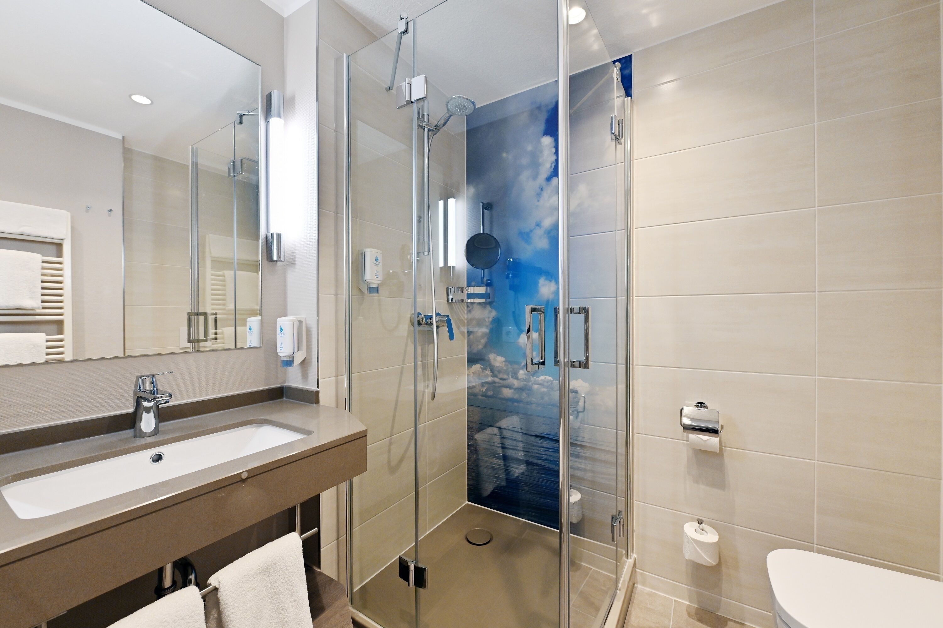 Une salle de bain moderne avec une douche à parois de verre, un lavabo et des toilettes.