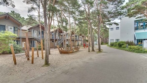 A pathway leading to a row of wooden cabins with a wooden boat in the center.