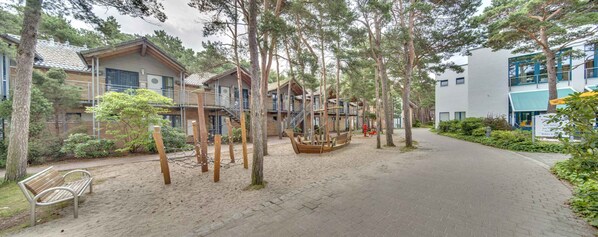 A pathway leading to a row of wooden cabins with a wooden boat in the center.