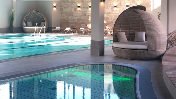 A pool area with a circular seating area and lounge chairs.