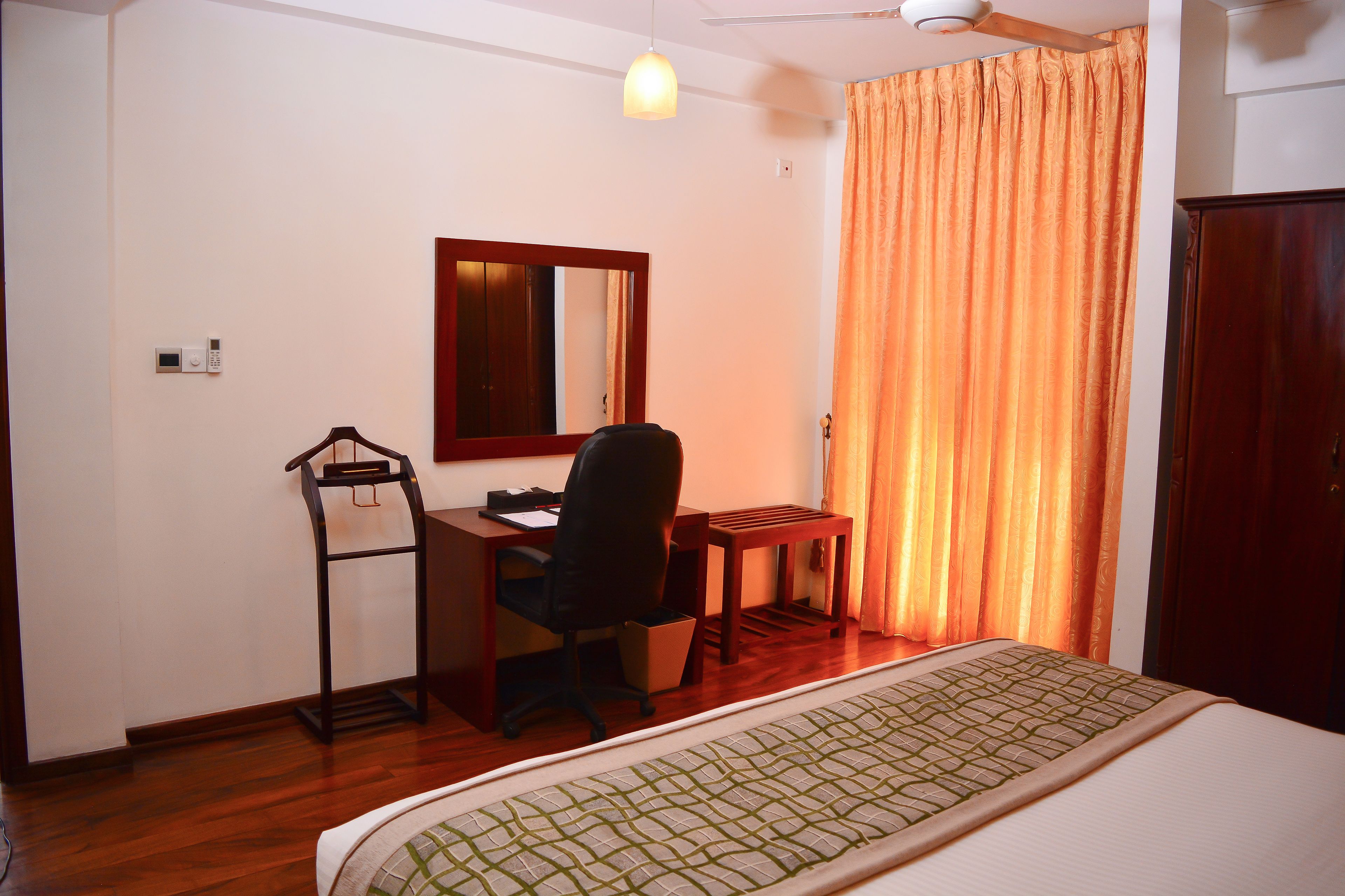 Une chambre d’hôtel avec un lit, un bureau, une chaise et un miroir.