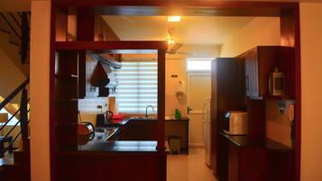 A modern kitchen with a central island, built-in appliances, and a staircase leading to another level.