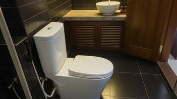 A modern bathroom with a white toilet, a sink, and a shower.