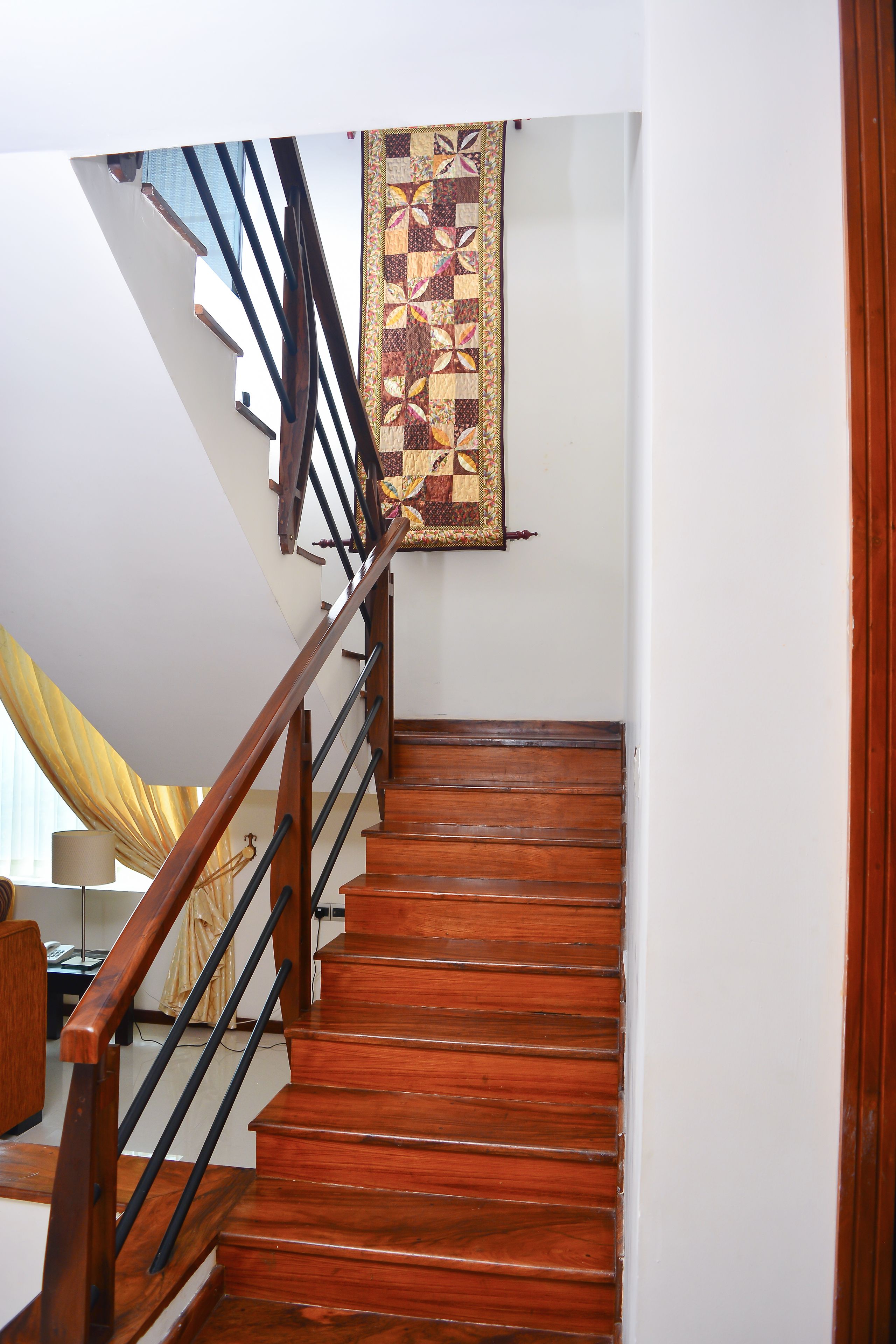 Una escalera de madera con barandilla y un tapiz decorativo en la pared.