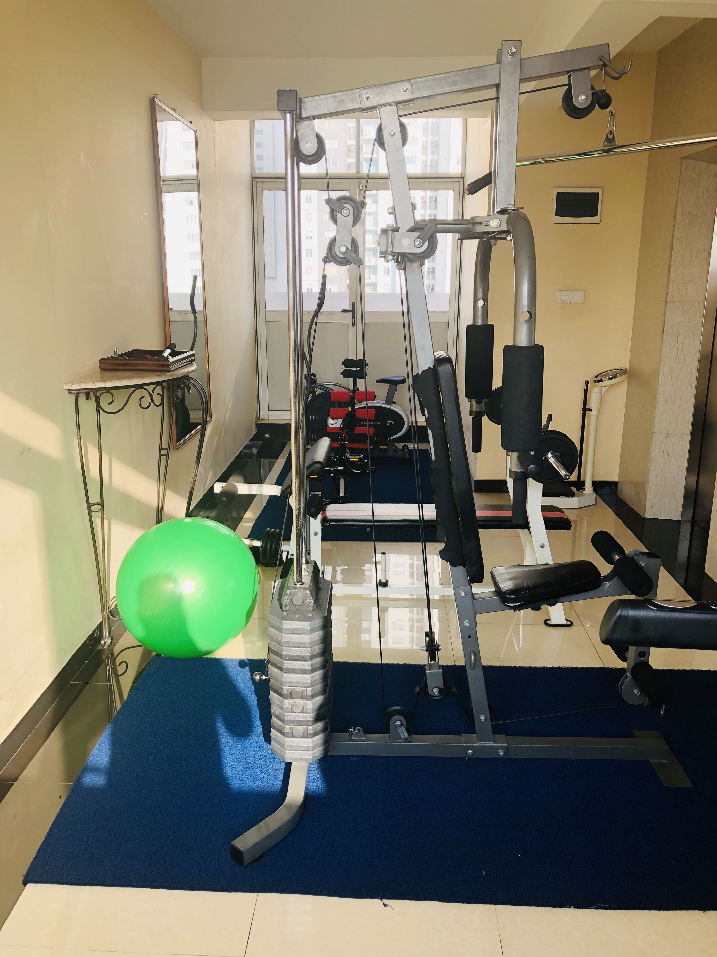 A gym with exercise equipment, a blue mat, and a green exercise ball.