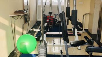 A gym with exercise equipment, a blue mat, and a green exercise ball.