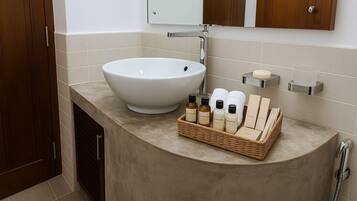 A bathroom with a large white sink, a mirror, a wooden cabinet, and a wicker basket containing toiletries.