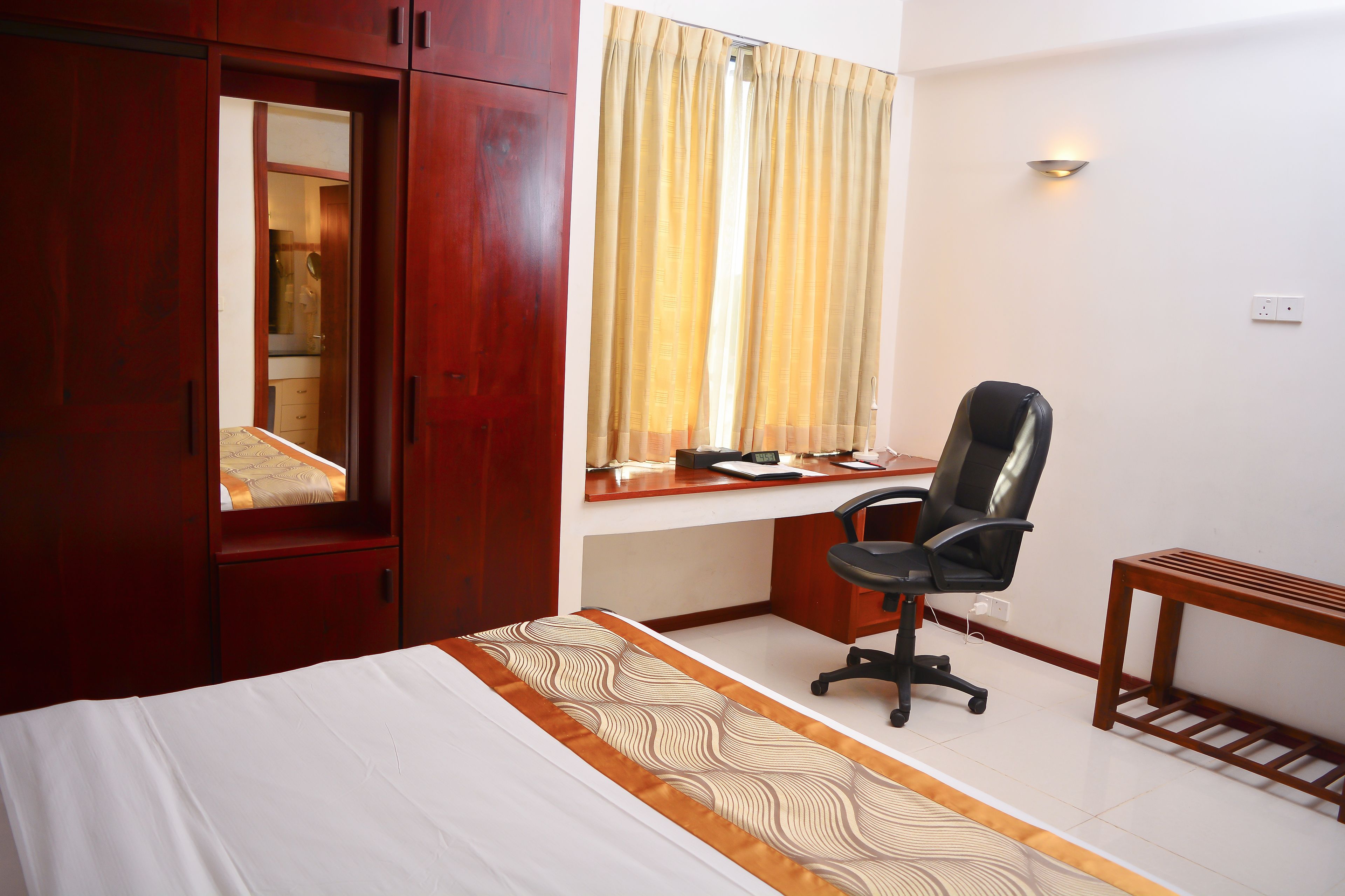 A hotel room with a bed, a desk, a chair, and a wardrobe.