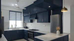 Une cuisine moderne avec des meubles de couleur bleu foncé, un réfrigérateur en acier inoxydable, une cuisinière à gaz et un plan de travail en marbre.