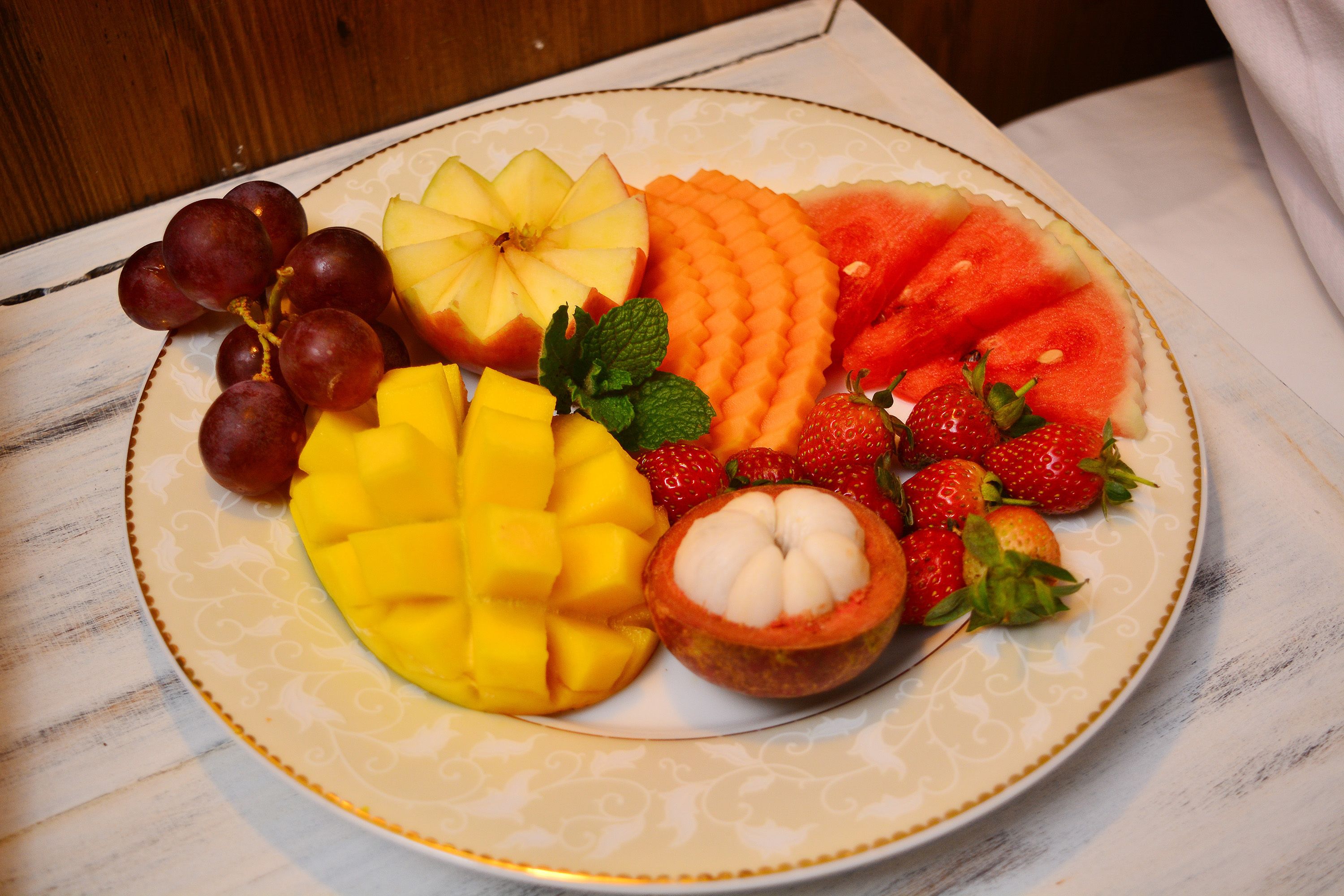 Ein Teller mit einer Auswahl an Früchten, darunter Trauben, Apfelscheiben, Wassermelone, Mango, Erdbeeren und eine halbe Guave.