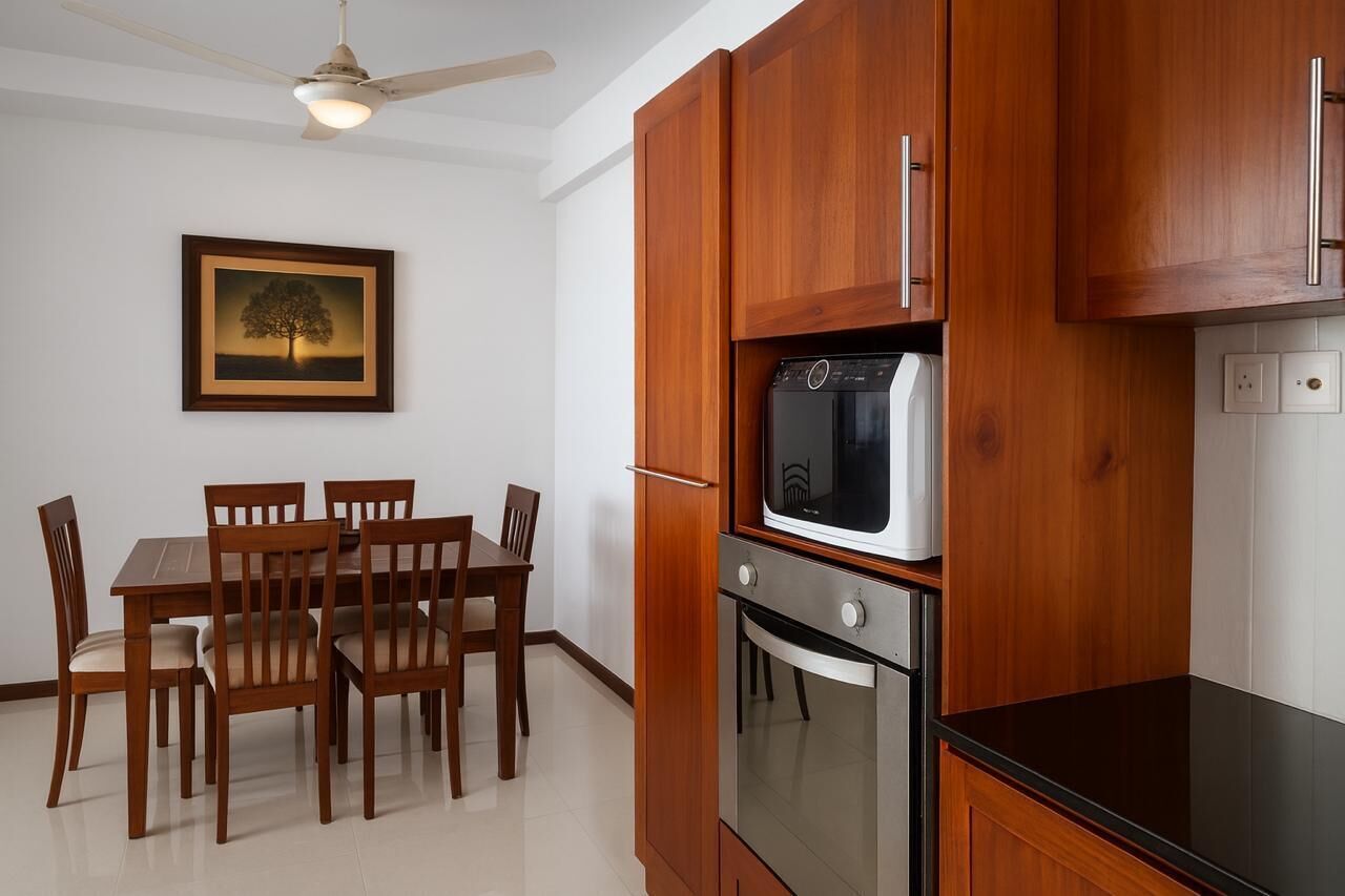 Cozinha compacta com armários de madeira, forno embutido e micro-ondas.
