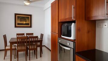 Cozinha compacta com armários de madeira, forno embutido e micro-ondas.