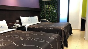 Hotellihuone, jossa on kaksi sänkyä, työpöytä, jossa on puhelin, tuoli ja viherseinä.