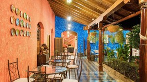 Un restaurant avec un sol à carreaux, des piliers en bois et un mur décoré de mosaïques bleues.