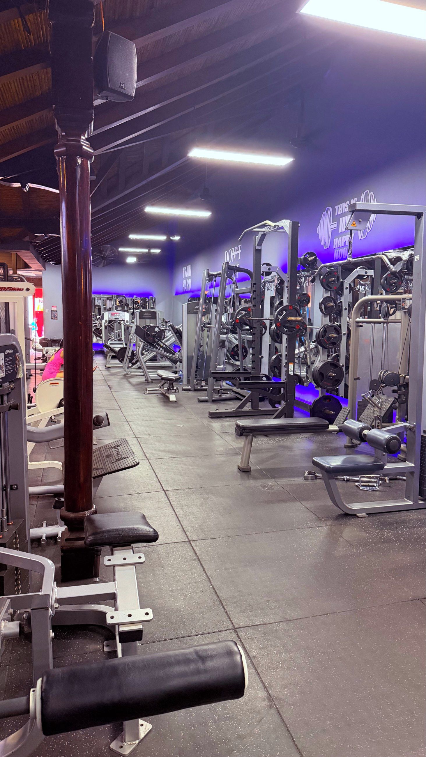 Ein Fitnessstudio mit verschiedenen Trainingsgeräten, darunter Kraftmaschinen und Kurzhanteln.